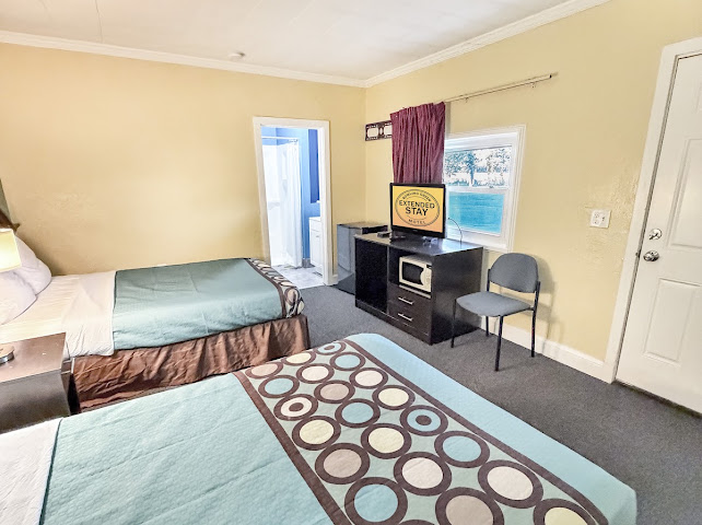 Guest room with two beds, television, desk, and seating