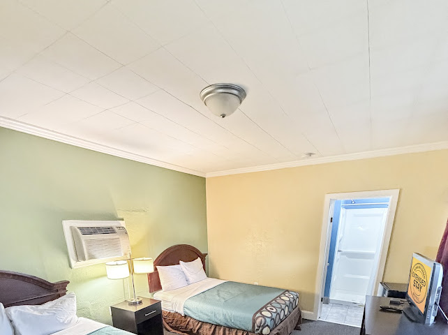 Guest room with two beds, lighting, air conditioning, and bathroom access
