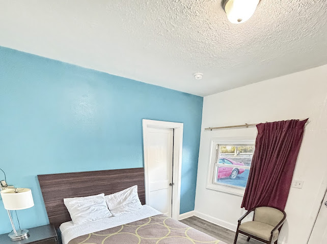 Guest room with a turquoise accent wall, made bed, window, and seating